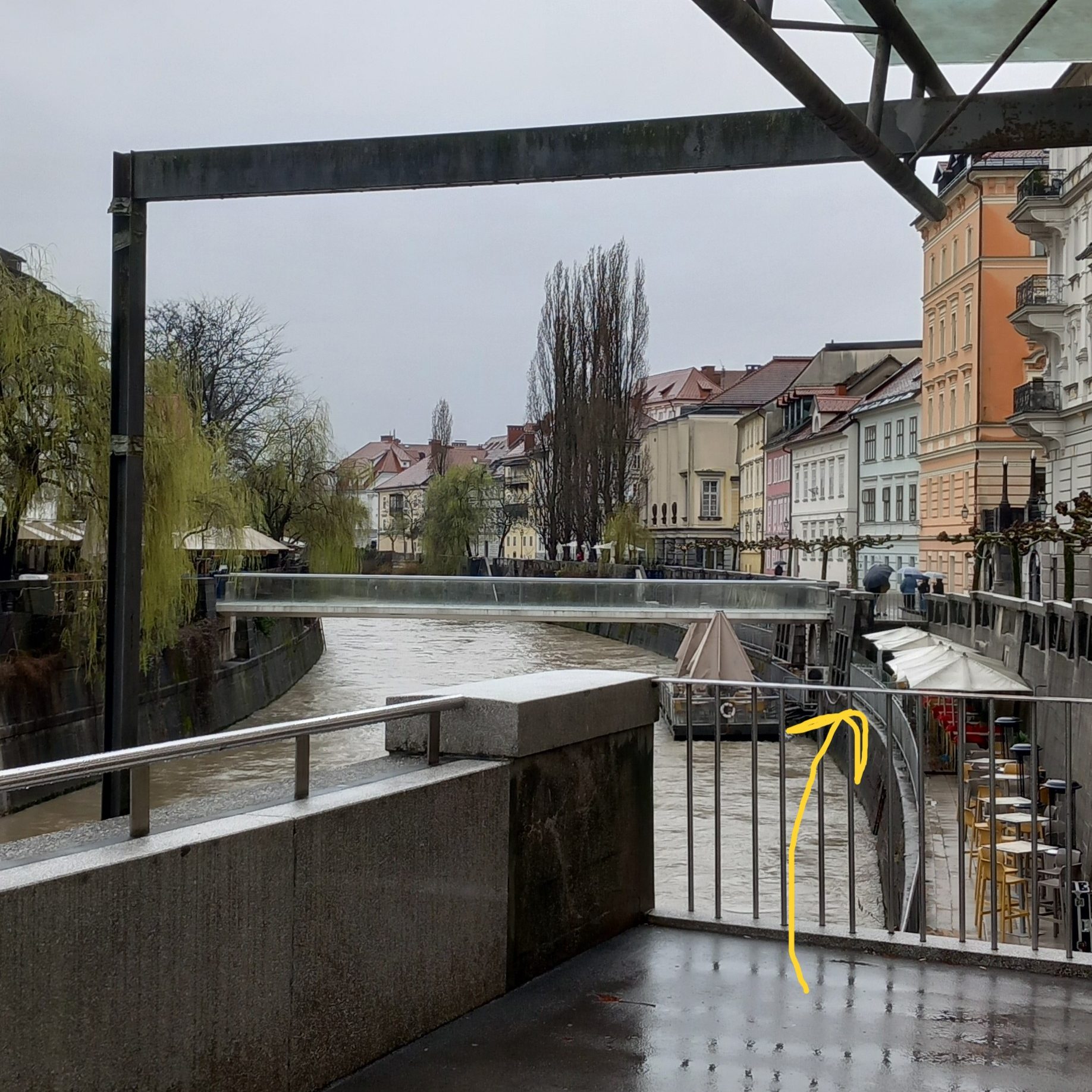 A photo of a river canal in Ljubljana, showing on the right the platform on the river that is part of a cafe called Makalonca.