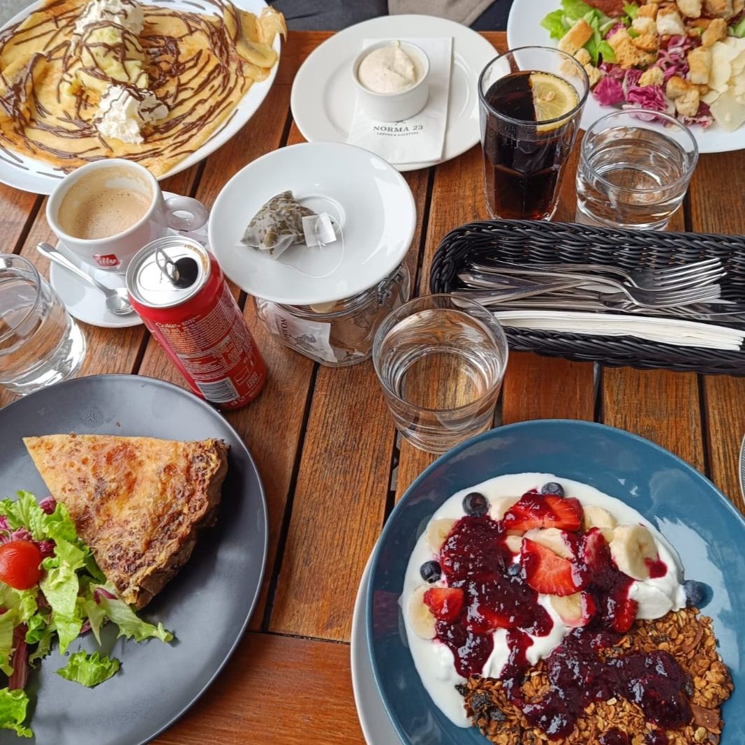Brunch at Norma 23, a French creperie in Ljubljana, Slovenia. Four plates with different things from the menu: quiche, granola, a salad, and a crepe.