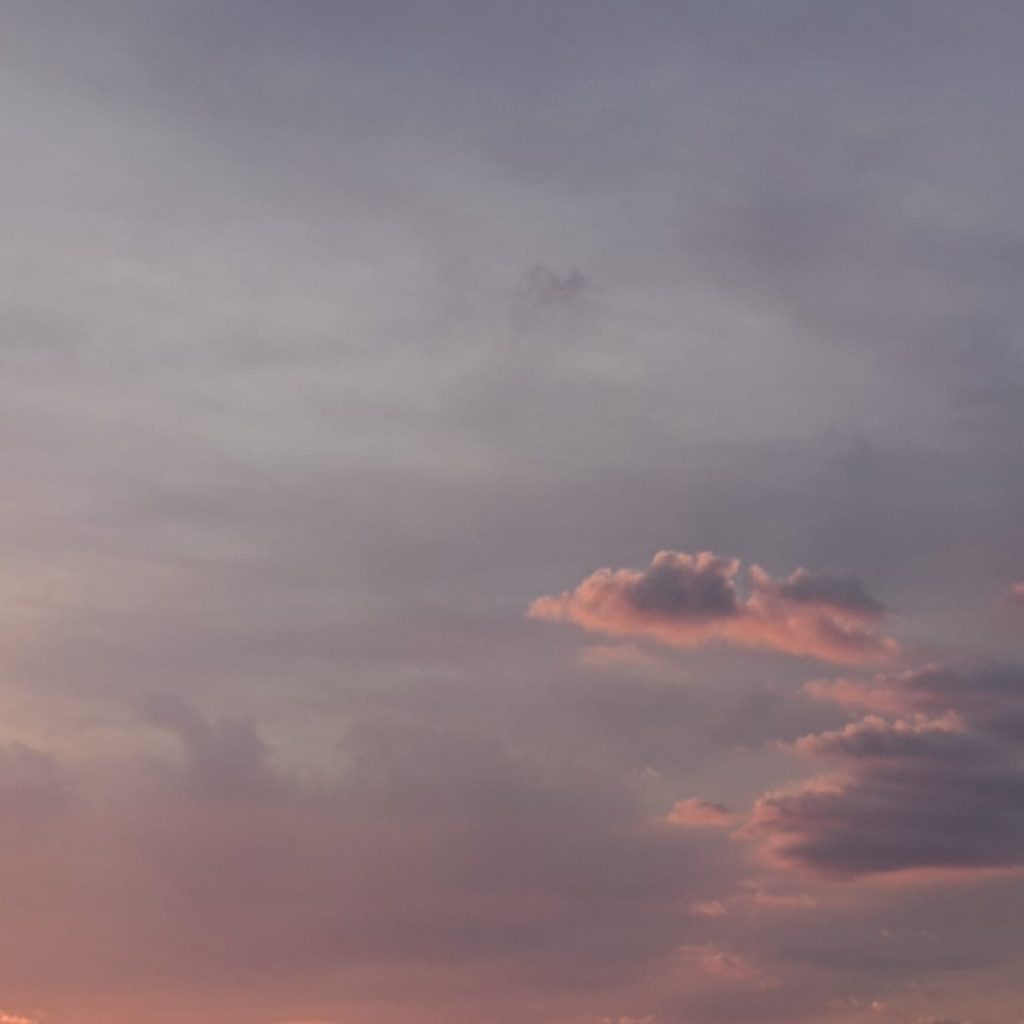 A serene sky with soft clouds in shades of pink and purple during sunset.