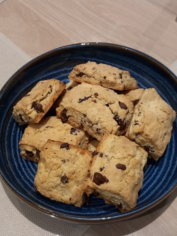 A blue plate filled with freshly baked chocolate chip cookies, arranged neatly.